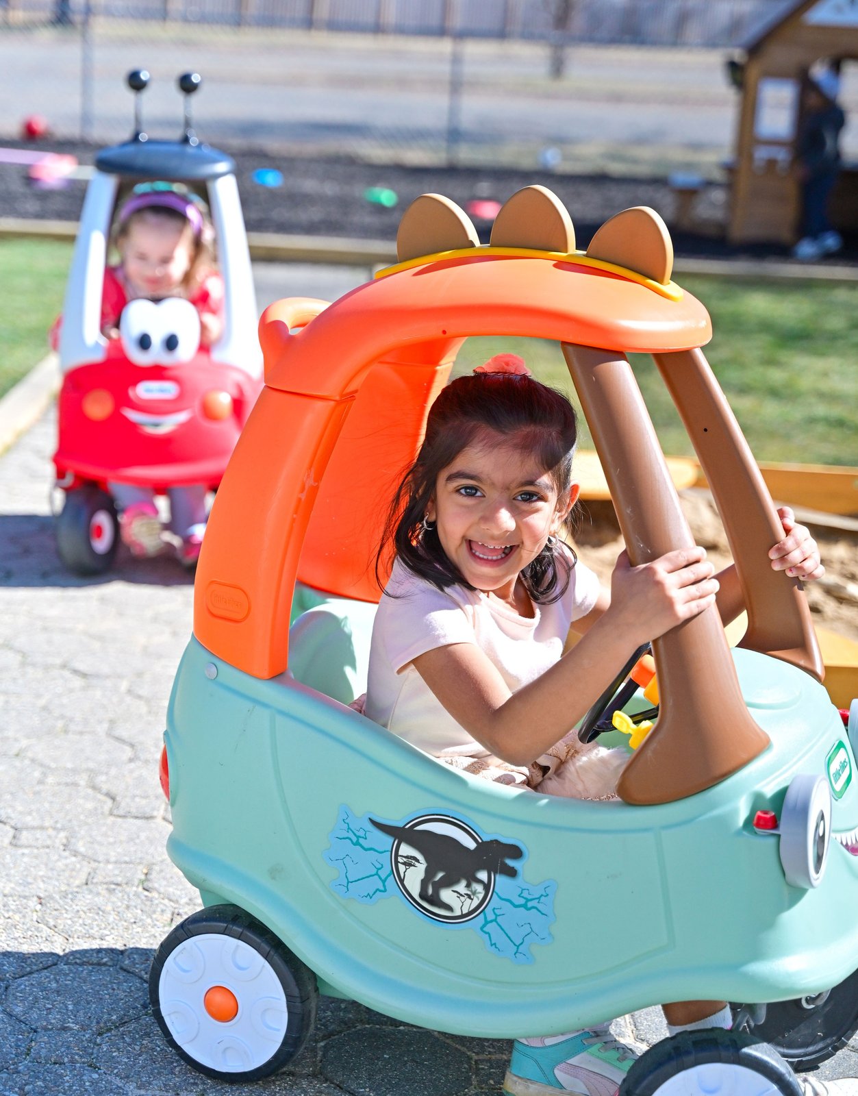 Smiling girl in outdoor toy car at summer camp